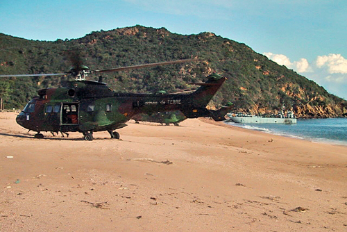 Hélicoptères Cougar sur la plage, au fond, un chaland de débarquement vient d'accoster
