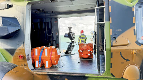 Sur cette photo on aperçoit des caissons oranges qui contiennent des canaux de sauvetage en cas d'amerrissage. Sur tous les NH90 une mitrailleuse est montée sur la gauche de l'appareil, pour libérer la portère droite et faciliter l'embarquement des passagers